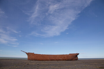 Rusty hull of the old British ship Marjory Glenn burned down in 1911. It lies today on the shores...