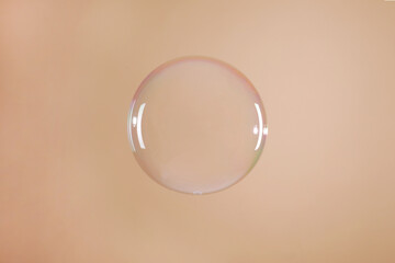 One beautiful soap bubble on light brown background