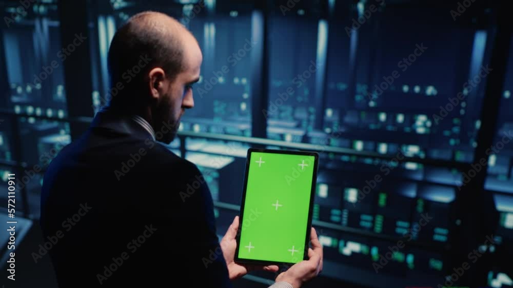 Poster network engineer doing system check on green screen, using tablet showing chroma key display with is