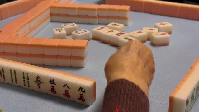 Close up, anonymous elderly woman's hand playing mahjong