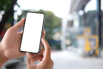 Close up view of man hands holding smart phone at outdoor in city with sunrise and building background.