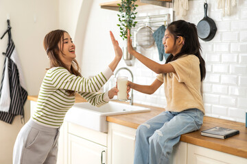 Portrait of enjoy happy love asian family mother with little asian girl smiling and having protein breakfast drinking and hold glasses of milk on counter in kitchen at home.Diet concept.healthy drink