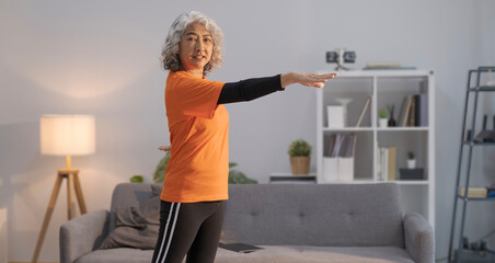 Fototapeta na wymiar Active mature woman doing her workout routine, exercising in living room at home. Healthy lifestyle concept.