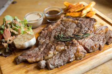 Rib Eye Steak in wooden plate on the wood table in restaurant