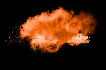 Orange powder explosion on black background. Orange color dust splash.