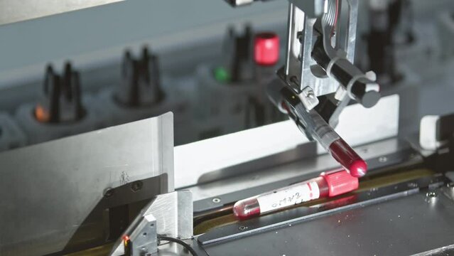 Machine reaching for and picking up a blood sample from a production belt. Blurred background. High quality 4k footage