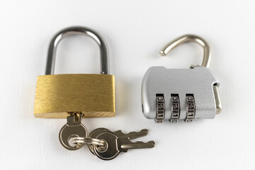 白背景で撮影した鍵の開いた南京錠とダイアルロック