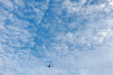 Plane cruising around the beautiful morning sky with lots of small clouds.