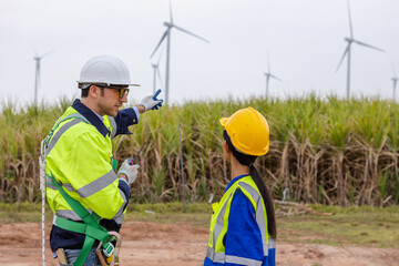 Team engineer of wind turbine worker pointing working about renewable energy at station energy power wind. technology protect environment reduce global warming problems.