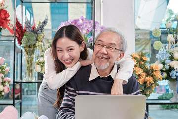 Asian young beautiful daughter teasing her father with love, senior male florist shop owner when...