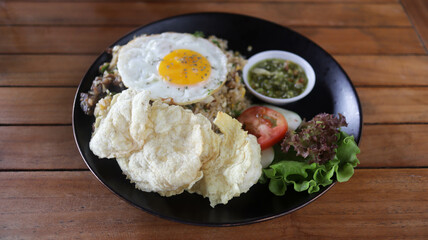 Village fried rice or "nasi goreng kampung" made with lots of toppings, tomato, fried egg, crisp, and special oiled mash chili some fresh vegetable.