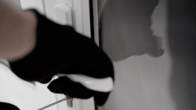 A man in a black glove tries unsuccessfully to break the lock of the door with a master key. Attempt to break the lock of a white plastic door