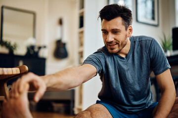 Obraz na płótnie Canvas Male athlete stretching his leg while exercising at home.