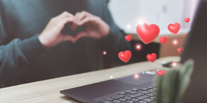 Long distance love, a man working on laptop computer with virtual red heart for application notification alert concept, love day, Valentine's Day.