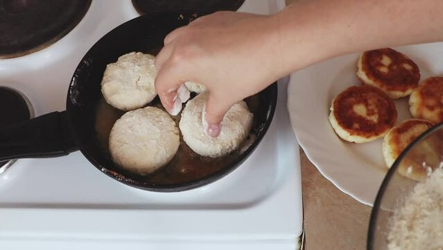 Women's hands put cottage cheese pies on a hot pan. Cheesecakes are fried in a pan. The process of preparing delicious homemade food. cheesecakes or cheesecakes. close-up. Cottage cheese balls, health