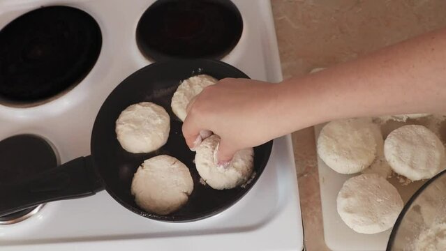 Women's hands put cottage cheese pies on a hot pan. Cheesecakes are fried in a pan. The process of preparing delicious homemade food. cheesecakes or cheesecakes. close-up. Cottage cheese balls, health
