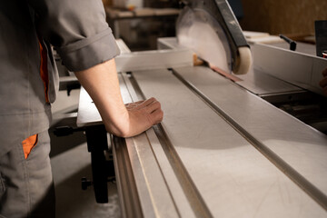 Process of production and manufacture of wooden furniture in furniture factory. Worker carpenter man processes wood on special equipment.