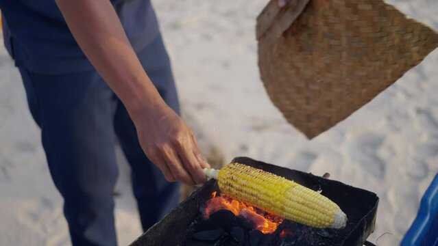 Cooking corn on a fire, Close-up, Man's hands hold a cob of corn over the fire. Slow motion