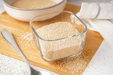 Wooden board with bowl of amaranth seeds on table, closeup