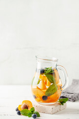 Detox infused water in glass. Refreshing summer homemade cocktail with fruit, berries and citrus