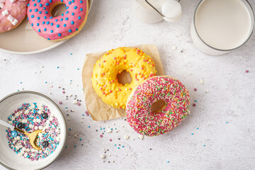 Parchment with delicious donuts and glass of milk on white table