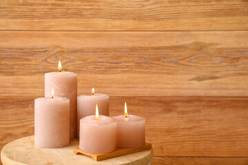 Fototapeta na wymiar Burning candles on table near wooden wall