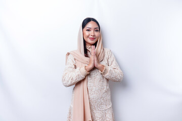 Naklejka premium Portrait of a young beautiful Asian Muslim woman wearing a hijab gesturing Eid Mubarak greeting