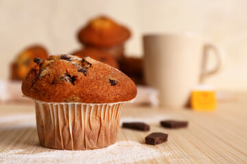 Delicious muffin with chocolate on beige wooden table