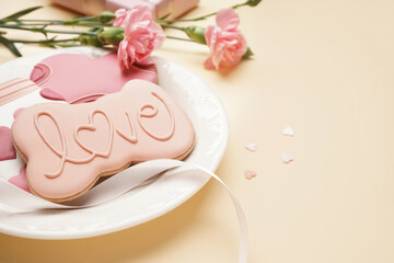 Plate with sweet cookies and carnation flowers on color background, closeup. Valentine's Day celebration