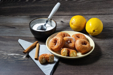 Homemade doughnuts fried with sugar and cinnamon on a wooden background.