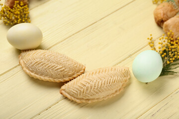 Frame made of flowers, eggs and shekarbura on yellow wooden background, closeup. Novruz Bayram celebration