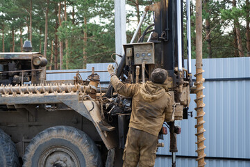 Team of workers with drilling rig on car are drilling artesian well for water in ground. Insertion...