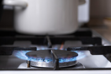 Ignition of the gas burner on the stove in the kitchen. Use of natural resources, economy, cooking on fire. Close-up