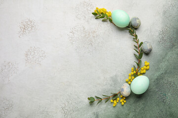 Frame made of Easter eggs, plant branches and mimosa flowers on grunge background