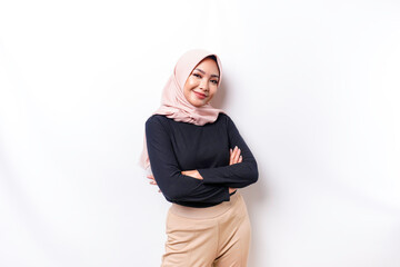 Portrait of a confident smiling Asian Muslim woman wearing hijab standing with arms folded and looking at the camera isolated over white background