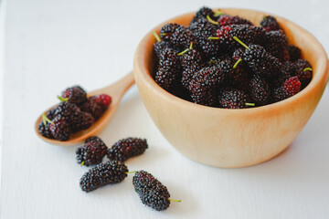 Black mulberry in wooden cup and wooden spoon It is a fruit of the berry family that is beneficial...