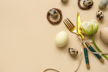 Table serving with Easter eggs and tulip flower on beige background