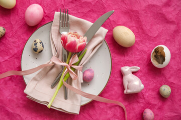 Table serving with Easter eggs, bunny and tulip flower on pink background