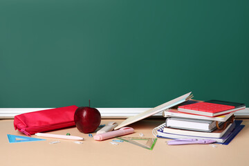 Different stationery with apple on color table against blackboard. Pi Day celebration