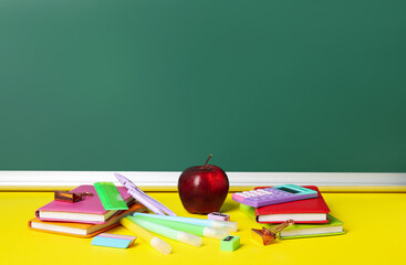 Different stationery and apple on yellow table against blackboard. Pi Day celebration