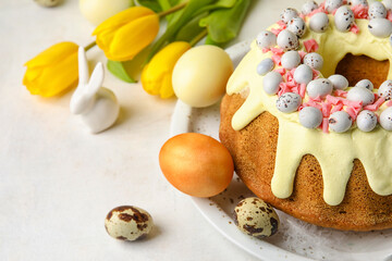 Plate with tasty Easter cake, eggs and tulip flowers on light background, closeup