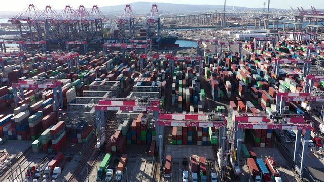 Daytime aerial view of an intermodal container shipping stock yard unloading vessels at port.