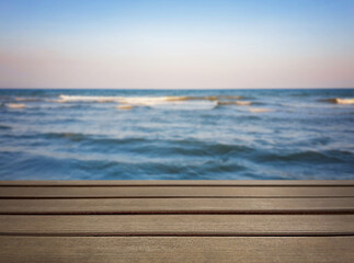 Natural, abstract, unfocused background. Seascape. An empty wooden base, a wooden table, a tabletop against the background of sunset, dawn on the seashore. Copy space