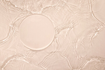 Empty clear glass circle podium on beige transparent calm water texture with waves in sunlight....