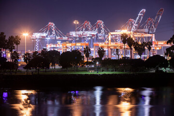 Fototapeta na wymiar Night time view of container cranes and cargo shipping containers being moved.