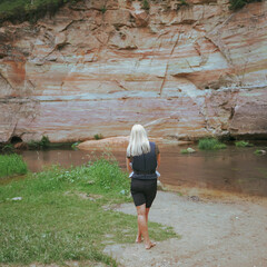 A girl in a life jacket stands near a river near a cliff in the Taevaskoja nature reserve.