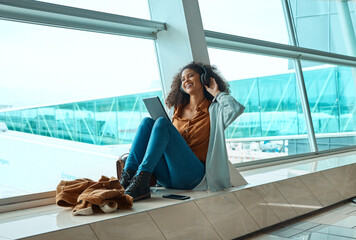 Black woman, headphones and travel with tablet, airport and listening to music with business trip...