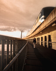 man walking on bridge as the skytrain passes