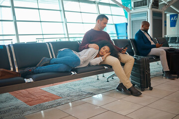 Tired, delay and couple at the airport for a flight, waiting and sitting in the lounge on a phone. Immigration, relax and woman sleeping with a man reading on a mobile while traveling for holiday - Powered by Adobe