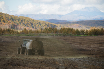 A muckspreader and tractor in an autumn field